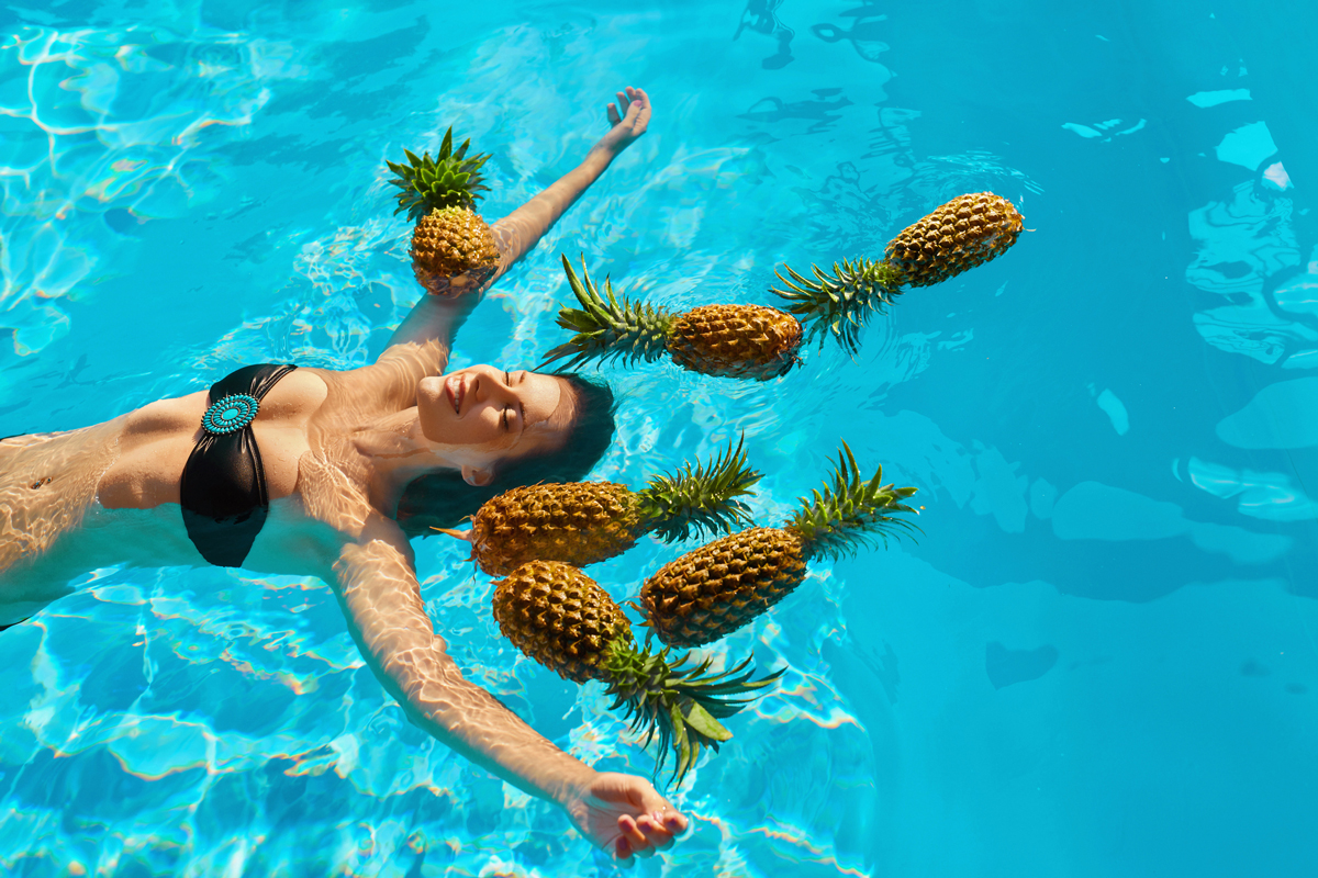 Девушка в бассейне с ананасами